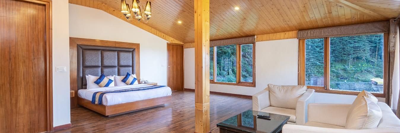 A spacious and luxurious hotel room with a king size bed, a sitting area, and large windows offering scenic views  | DLS Serenity Resort and Spa